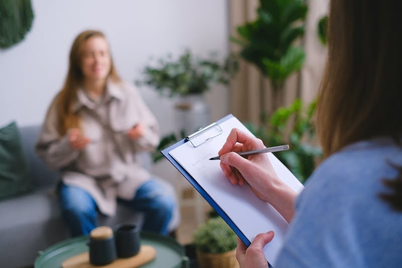 Therapeutin notiert während einer einfühlsamen Therapiesitzung in der elduran Logopädie